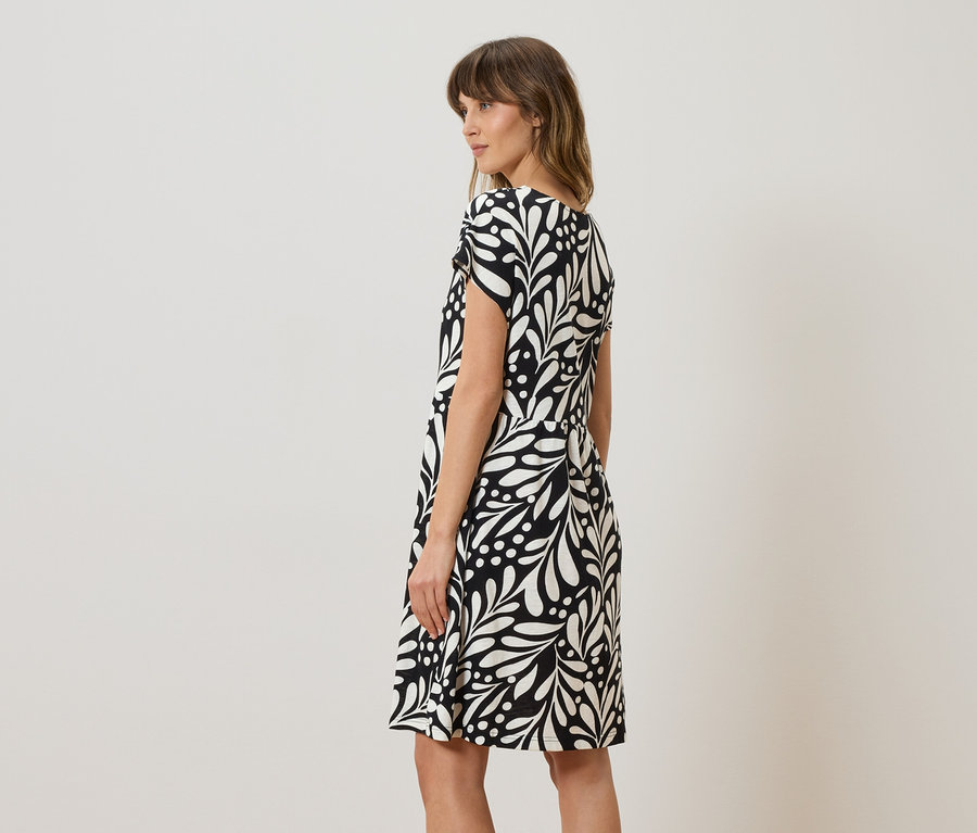 Femme portant une robe noire et blanche à motifs de feuilles.