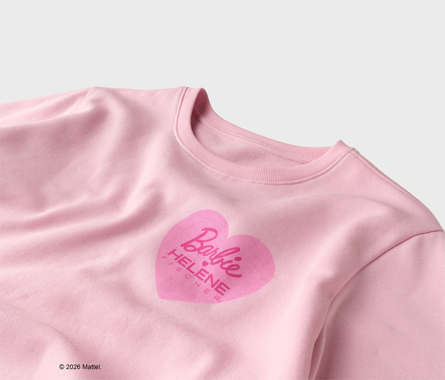 Vue détaillée d'un pull rose clair avec un imprimé coeur rose avec le logo Barbie et le nom Helene Fischer.
