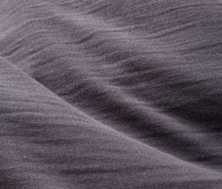 Gros plan d'un tissu gris drapé avec une texture et des plis visibles.