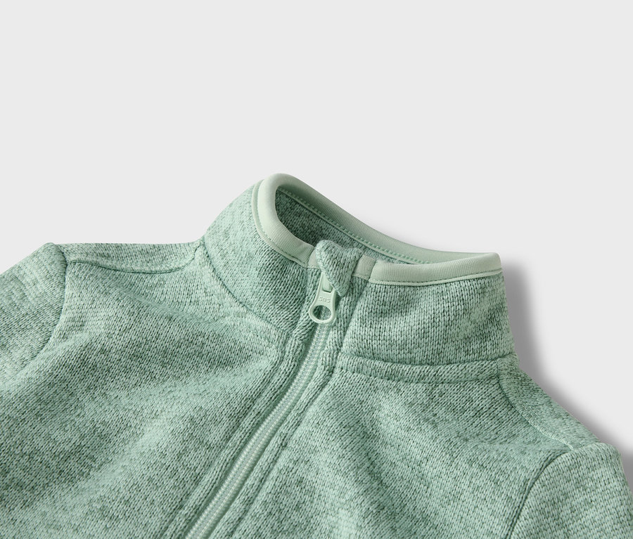 Gros plan sur une veste polaire vert clair zippée.