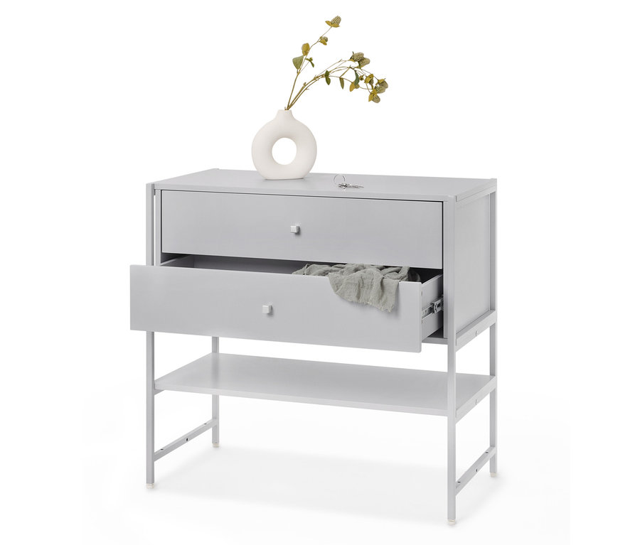 Un meuble à tiroirs gris avec deux tiroirs dont un est ouvert et une étagère en dessous, avec un tissu à l'intérieur et un vase avec une plante sur le dessus.