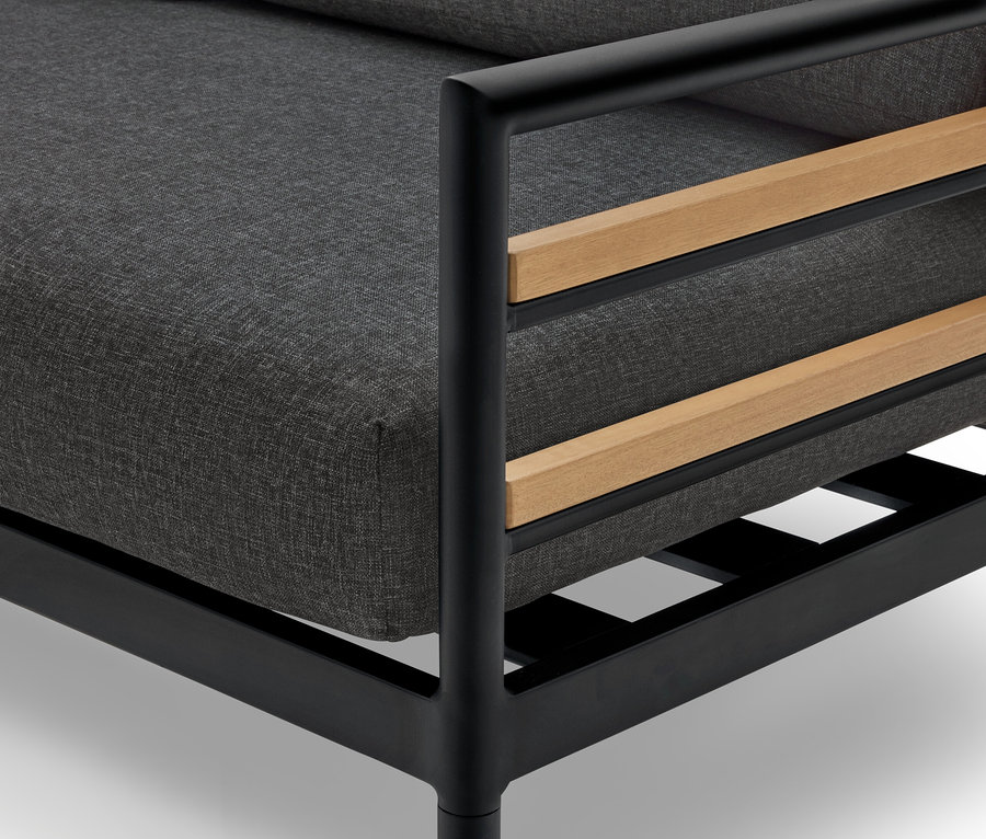 Gros plan d'un fauteuil avec un coussin gris, un cadre noir et des détails en bois.