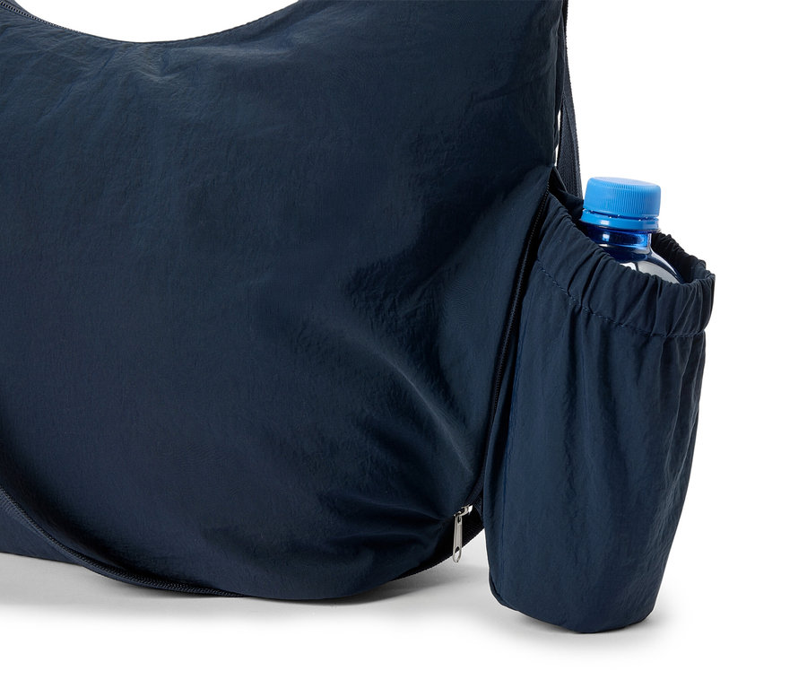 Gros plan d'un sac fourre-tout bleu marine avec une bouteille d'eau dans la poche latérale.
