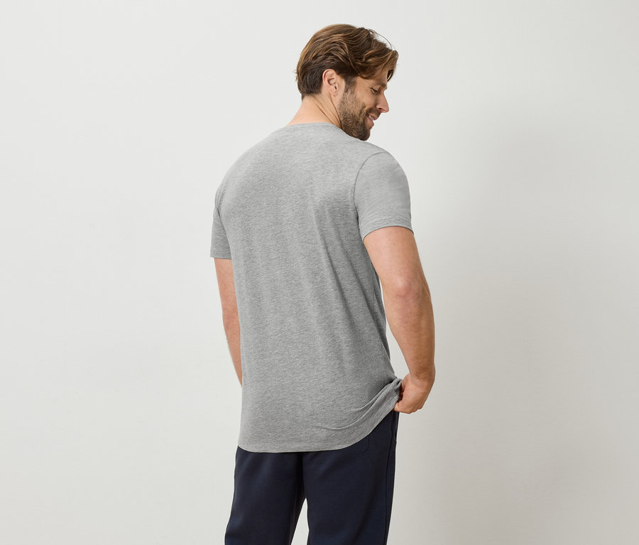 Homme vu de dos portant un t-shirt gris et un pantalon bleu.