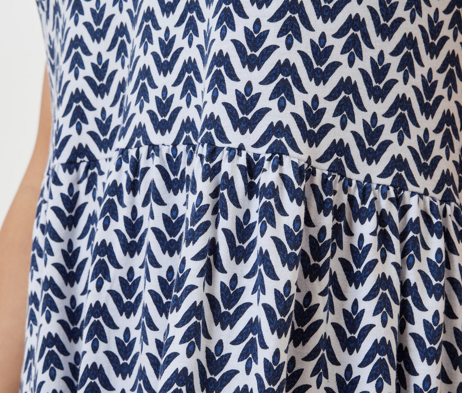 Gros plan d'une robe blanche avec un motif de feuilles bleues.