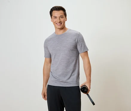 Un homme portant un t-shirt gris et un pantalon noir tient une bouteille d'eau.