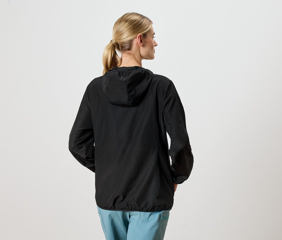 Femme de dos portant une veste noire et un pantalon bleu.