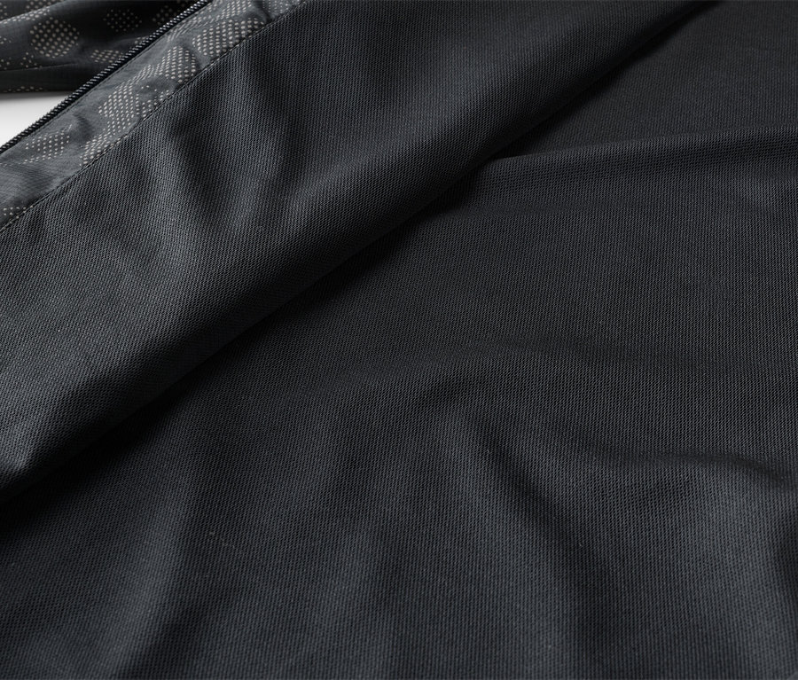Gros plan d'un tissu noir plié avec une fermeture éclair et un motif gris.