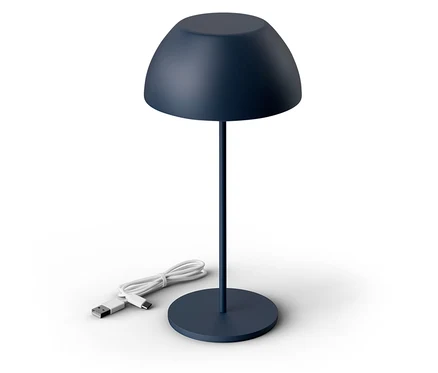 Une lampe bleu foncé est posée sur un fond blanc. Le câble de la lampe est posé à côté.