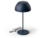 Une lampe bleu foncé est posée sur un fond blanc. Le câble de la lampe est posé à côté.