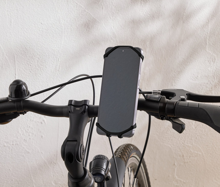 Gros plan sur le guidon d'un vélo avec un smartphone fixé par un élastique.