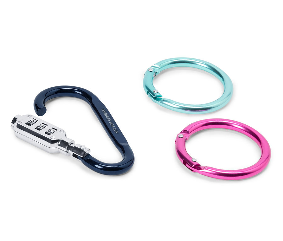Trois objets sont posés sur une surface blanche : un mousqueton avec un cadenas à combinaison en noir et argent et deux anneaux, un turquoise, un rose.