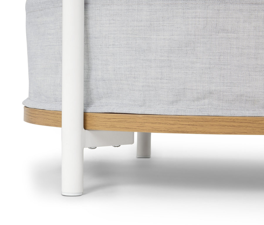 Gros plan d'un lit de bébé rond avec un tissu gris clair et une base en bois marron clair reposant sur un cadre blanc.