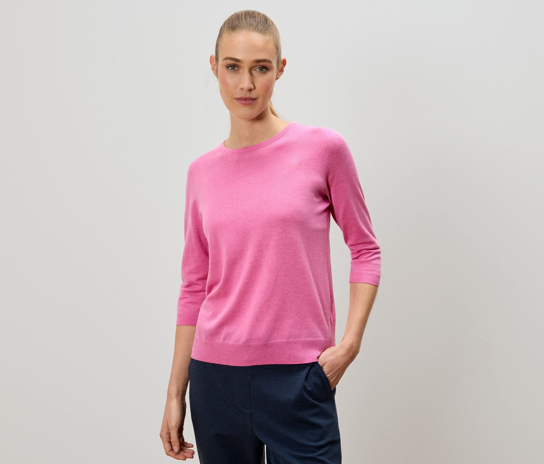 Femme portant un pull rose et un pantalon bleu marine.