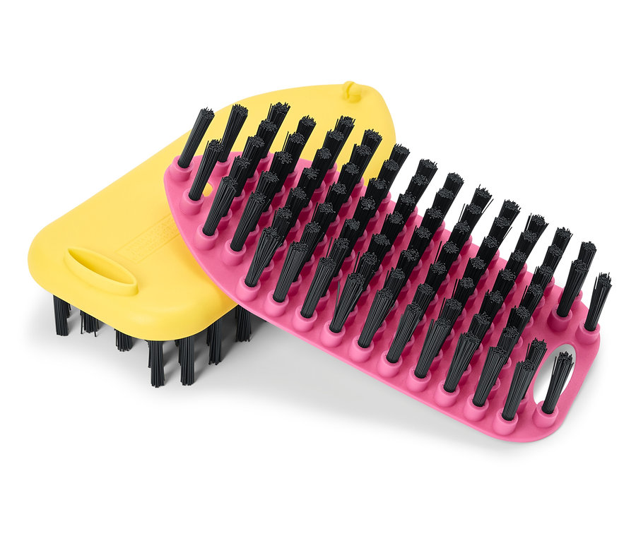 Une brosse jaune et une brosse rose à poils noirs sont posées l'une sur l'autre.