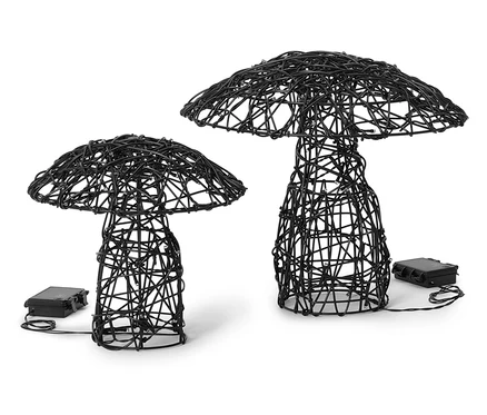 Deux lampes en fil de fer noir en forme de champignon de différentes tailles sont posées sur un fond blanc. Les lampes sont allumées.
