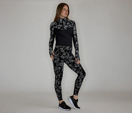 Femme portant un haut à manches longues et un legging à motifs floraux, avec des baskets noires.