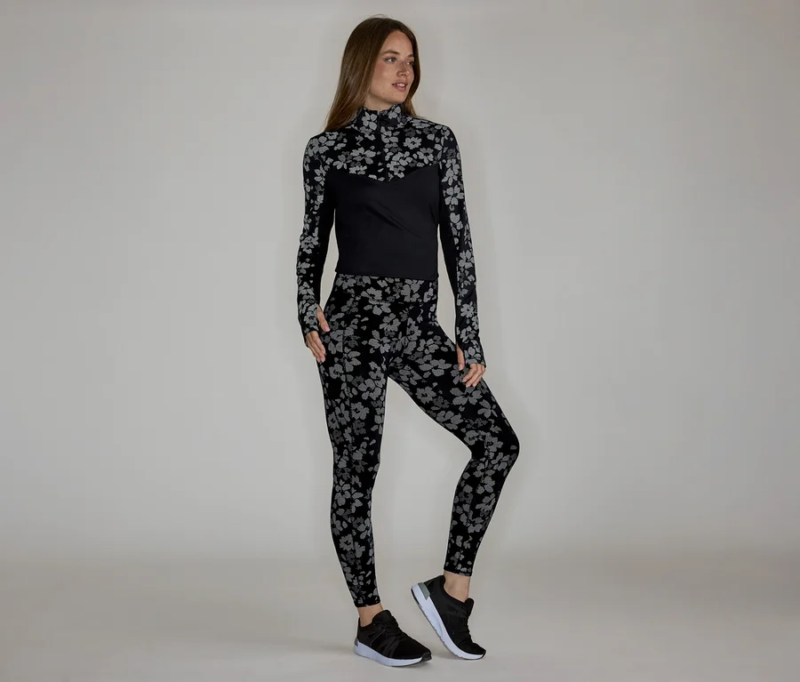 Femme portant un haut à manches longues et un legging à motifs floraux, avec des baskets noires.