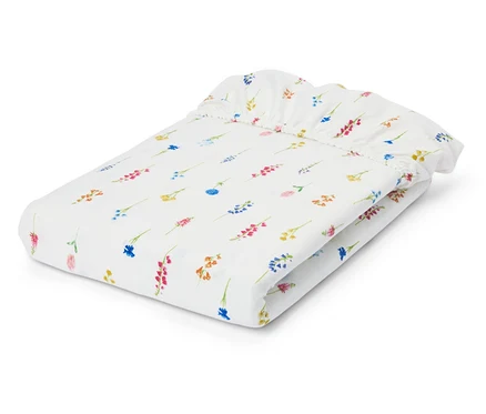 Drap-housse blanc plié avec motif floral.