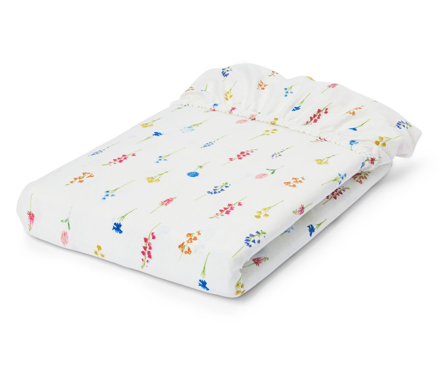 Drap-housse blanc plié avec motif floral.