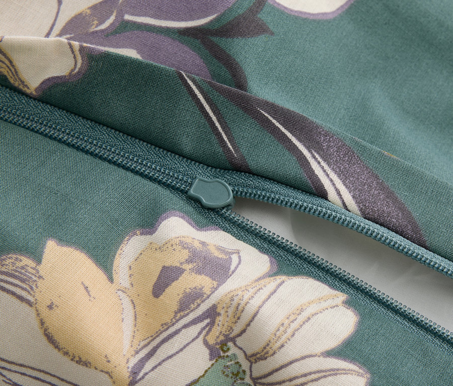 Gros plan d'une fermeture éclair sur un tissu verdâtre à motifs floraux.