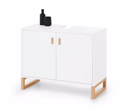 Meuble sous-lavabo blanc à 2 portes avec poignées et pieds en bois. Une bouteille pompe noire et une tasse sont posées sur le côté gauche du dessus.