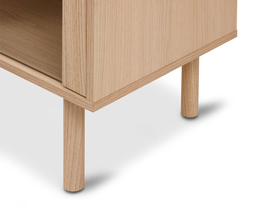 Gros plan du coin inférieur d'un meuble en bois clair avec deux pieds ronds en bois, montrant un compartiment ouvert.
