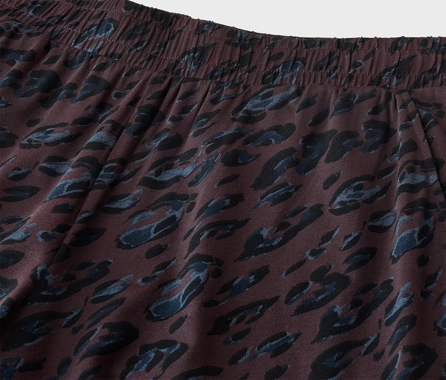 Gros plan d'un pantalon marron foncé avec une taille élastique et un motif léopard bleu et noir. Une ouverture de poche est visible sur le côté droit.