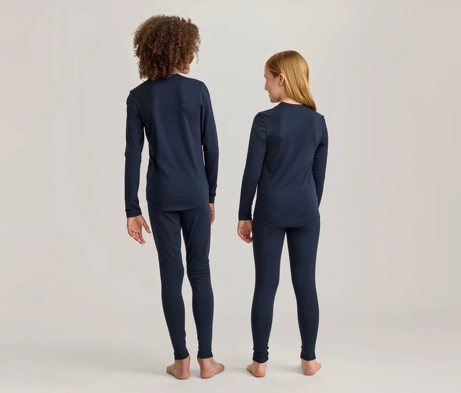 Deux enfants, un garçon et une fille, se tiennent dos à la caméra, vêtus de hauts à manches longues et de leggings bleu marine. Le garçon a les cheveux bouclés, la fille les cheveux blonds et lisses.
