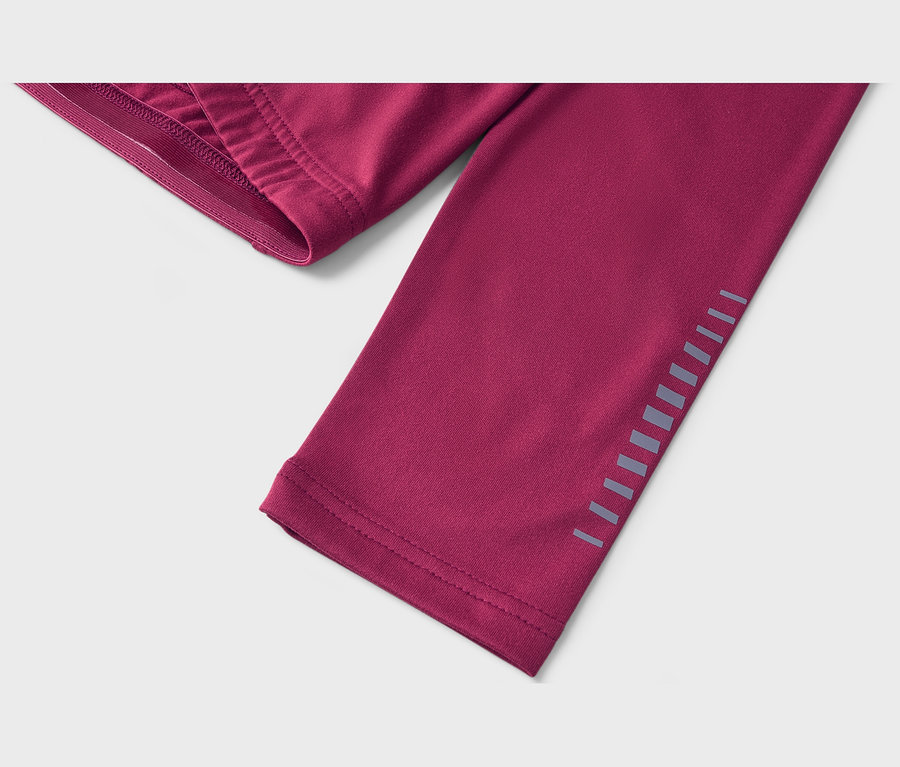 Gros plan d'un vêtement de sport magenta avec une ceinture élastique en haut à gauche et des bandes réfléchissantes sur le côté.