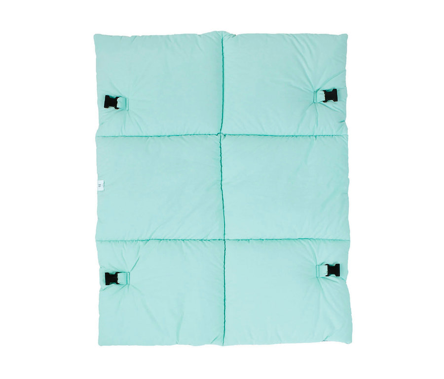 Un tapis ou une couverture rectangulaire rembourrée de couleur vert menthe, avec six sections matelassées. Quatre boucles en plastique noir sont attachées près des coins, et une petite étiquette blanche CE est visible sur le côté gauche.