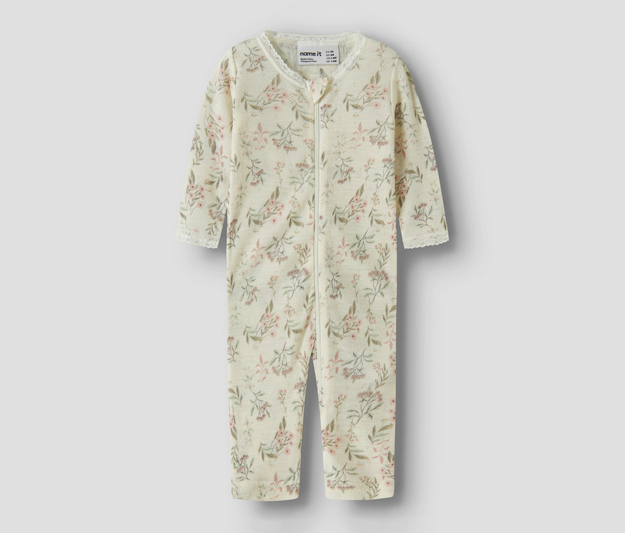 Combinaison bébé crème à motif floral rose et vert, avec une fermeture éclair sur toute la longueur et une bordure en dentelle blanche au col et aux poignets.
