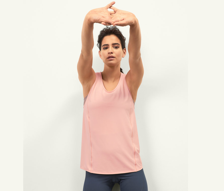 Femme les mains au-dessus de la tête portant un haut de sport.