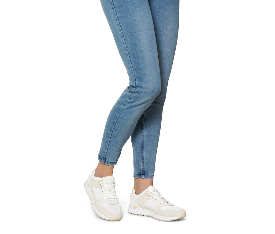 Jambes d'une femme portant un jean et des baskets en cuir velours.