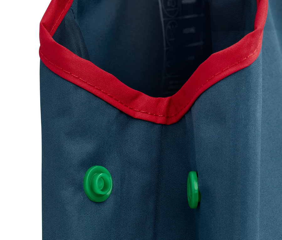 Gros plan sur un pantalon de pluie bleu en matériaux recyclés, bordé de rouge, avec deux boutons-pression verts.