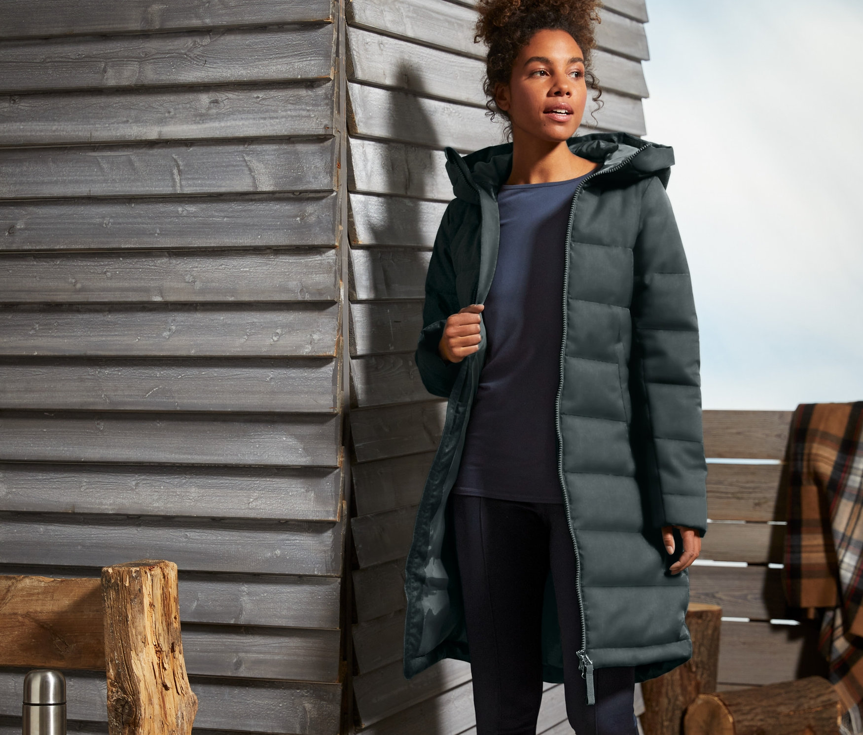 Femme marchant à l'extérieur et portant un manteau matelassé vert foncé.