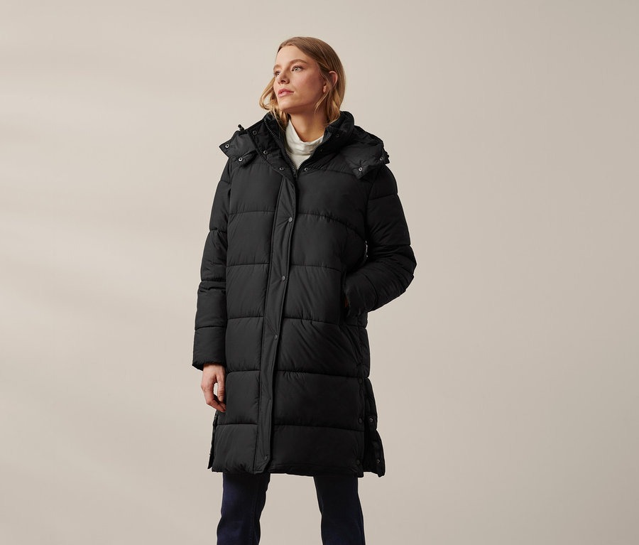 Femme portant un manteau matelassé à capuche noir.