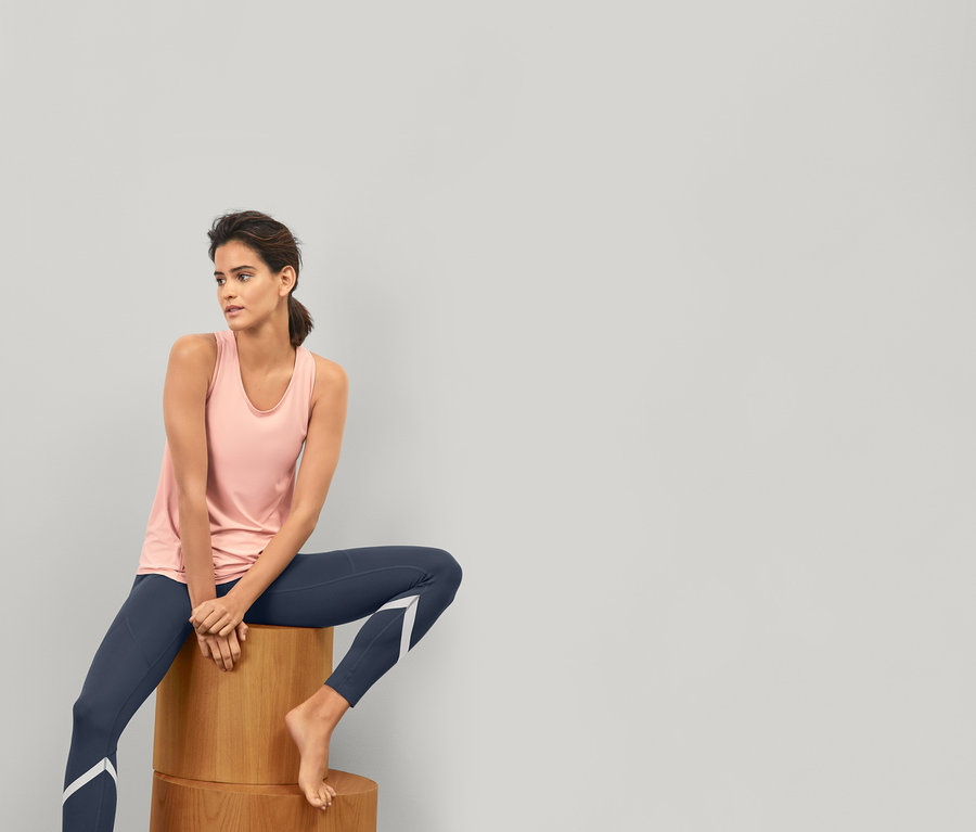 Femme assise sur des blocs de bois portant un legging de sport « Soft Touch » bleu et un haut de sport.
