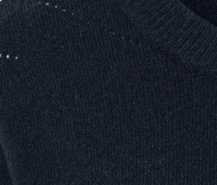 Détail d'un pull en maille bleu marine à motif ajouré.