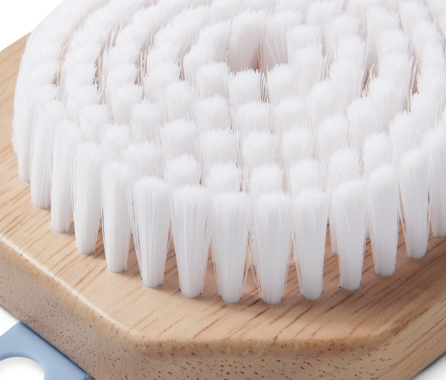 Gros plan d'une brosse de nettoyage pour le visage avec des poils blancs et un manche en bois.