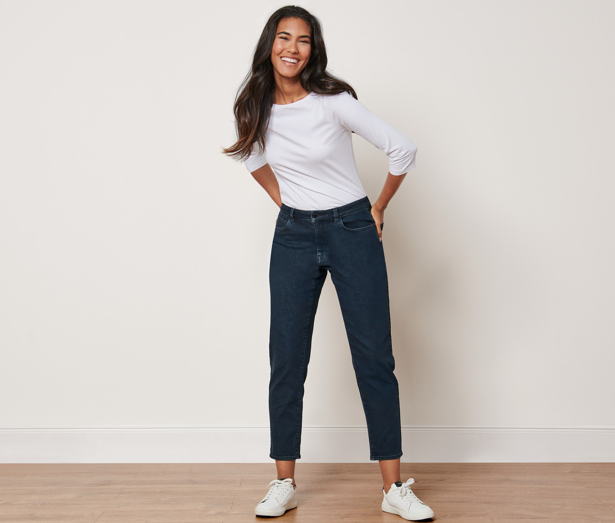 Femme posant en jean taille haute et t-shirt blanc.