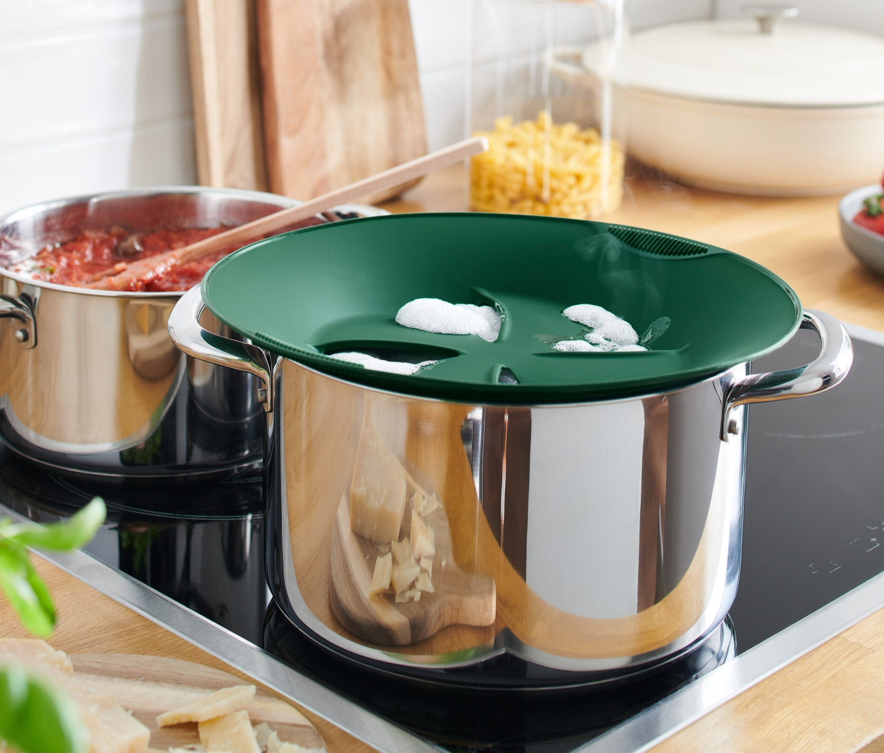 Deux casseroles sur une plaque de cuisson, une avec un système anti-débordement et l'autre avec de la sauce tomate.