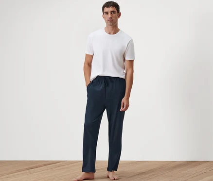 Un homme debout, les mains dans les poches de son pantalon relax.