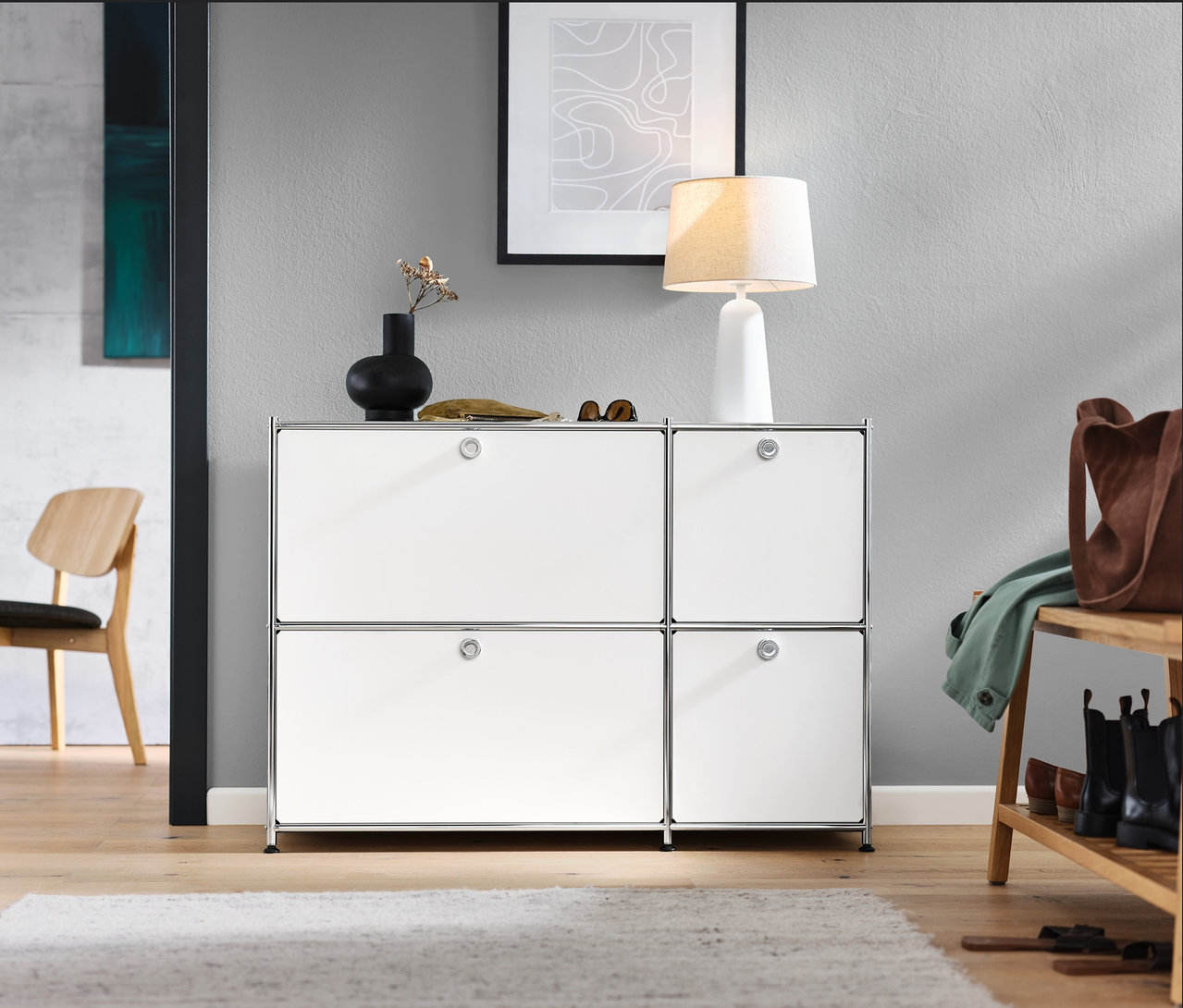 Hall d'entrée avec buffet bas « CN3 » blanc avec 4 abattants, chaise d'intérieur et lampe de table blanche avec abat-jour en tissu.