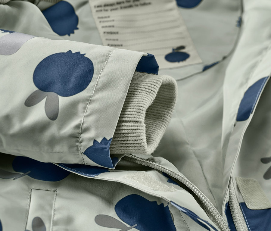 Gros plan sur une combinaison de pluie pour tout-petit avec un motif de myrtilles.