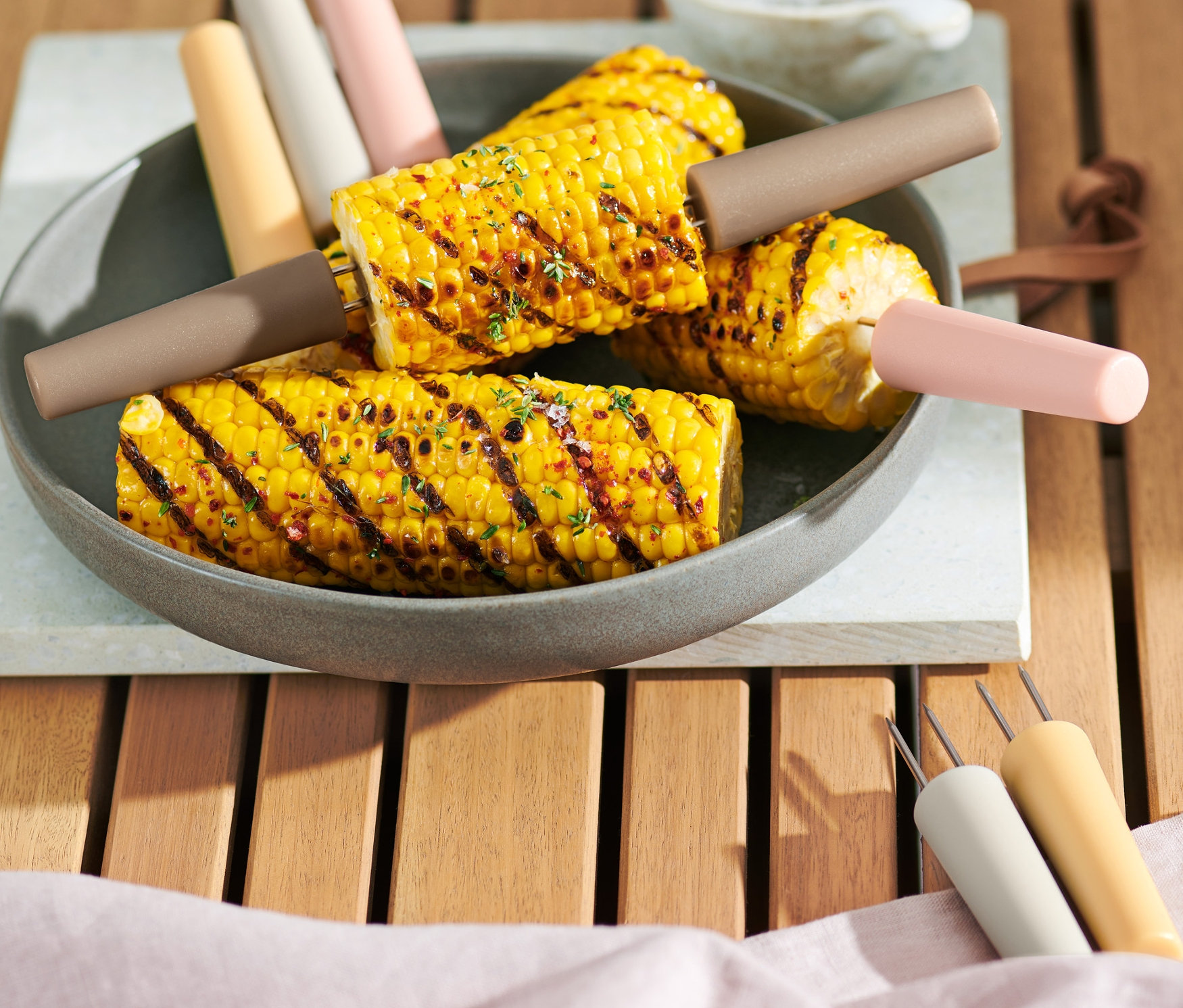 Maïs grillé avec 8 piques à épis de maïs dans une assiette.