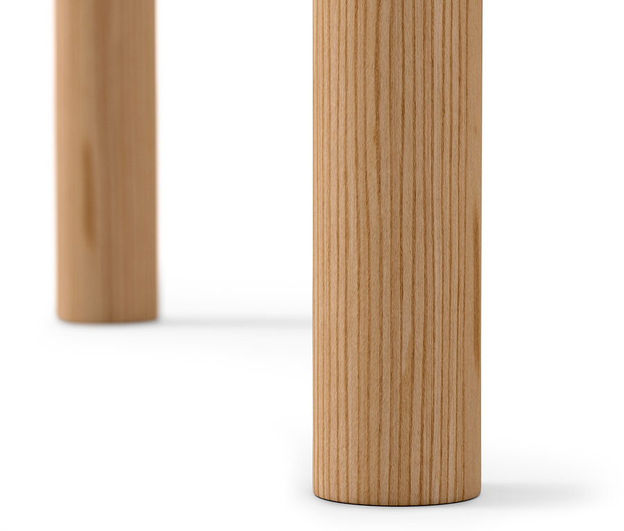 Gros plan sur deux pieds d'une table d'appoint ronde en bois clair sur fond blanc.