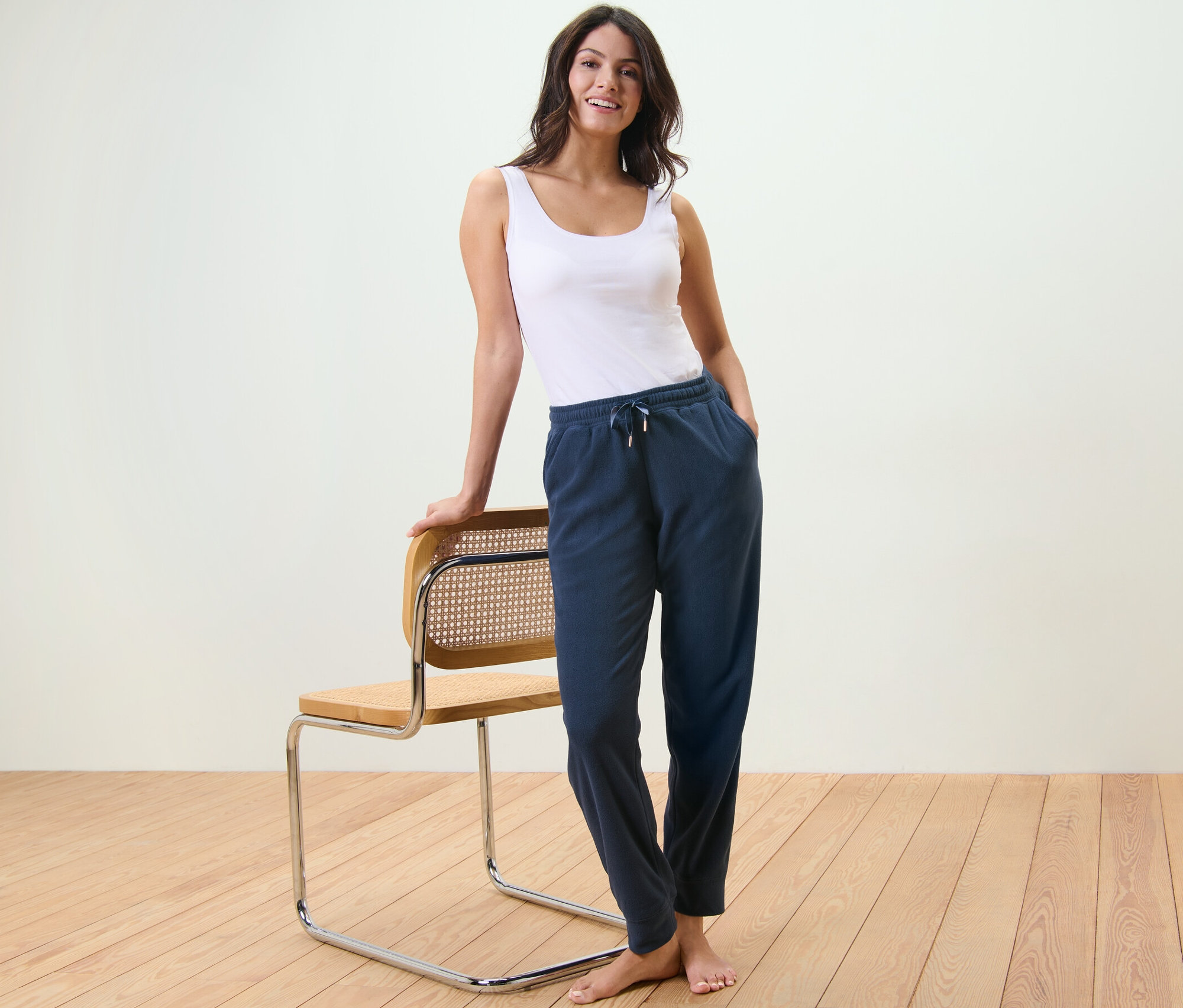 Femme debout appuyée sur une chaise portant un débardeur et un pantalon d’intérieur en polaire.