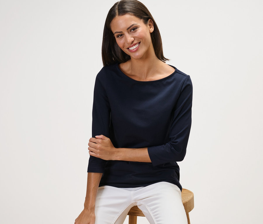 Femme assise sur un tabouret portant un t-shirt manches 3/4 bleu marine.