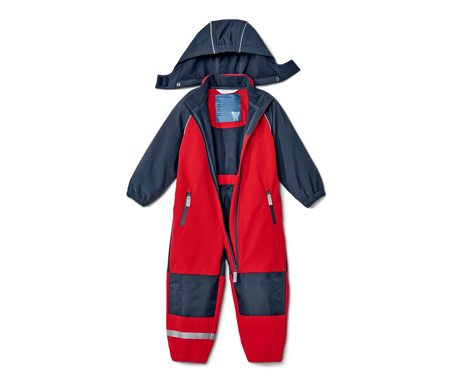 Combinaison en softshell rouge et bleu pour enfant, ouverte et posée sur le dos avec la capuche.